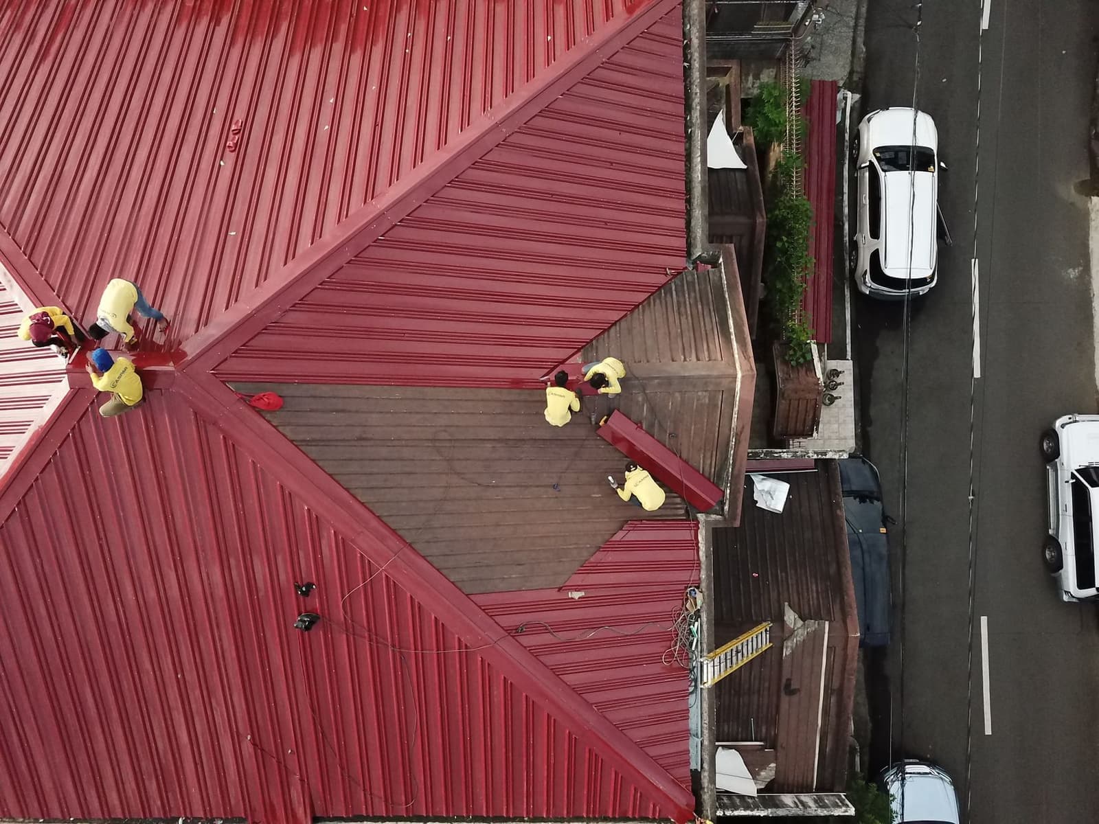 Aerial view of workers on red metal roof